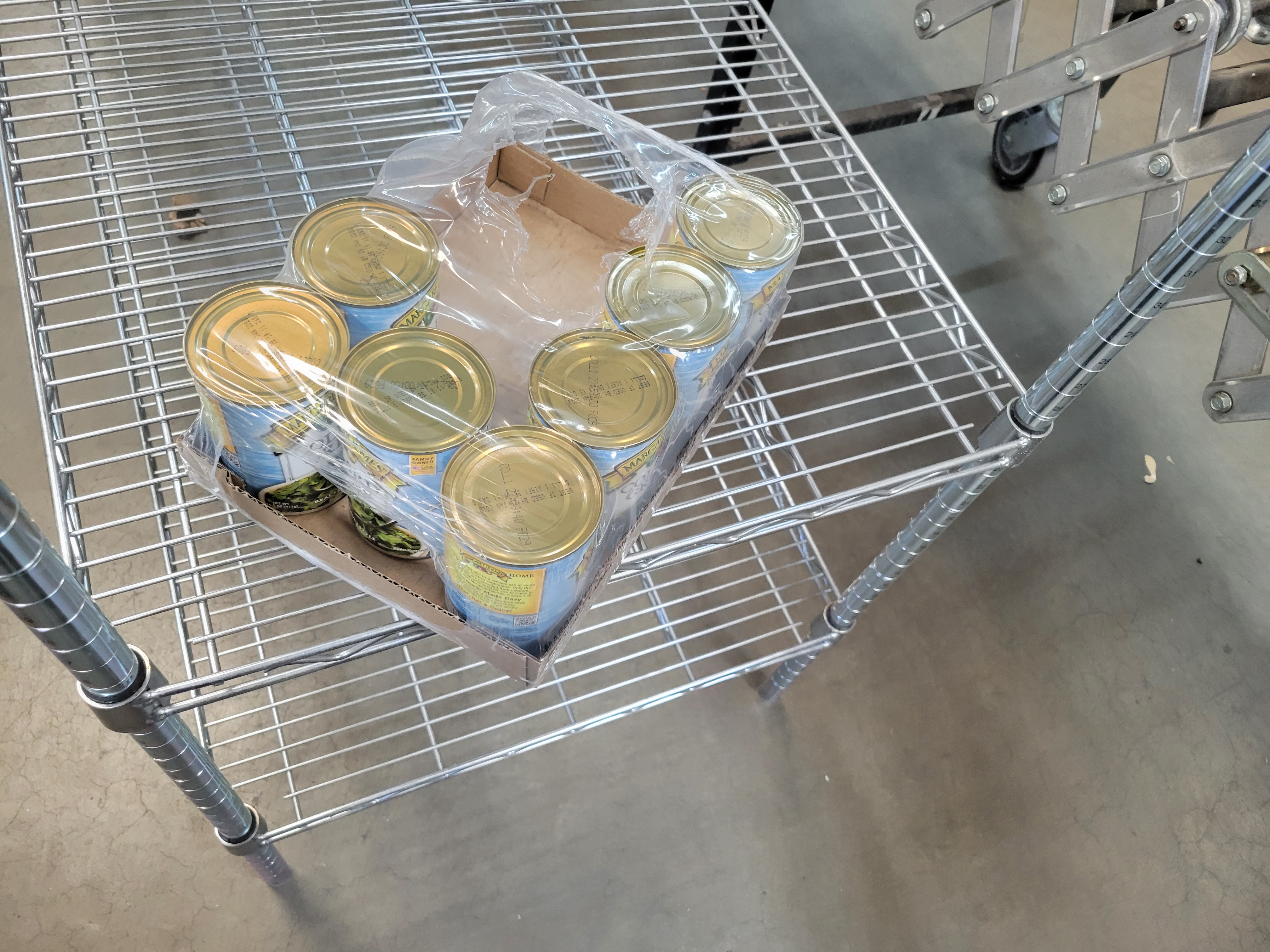 Cans in plastic and box on a shelf.